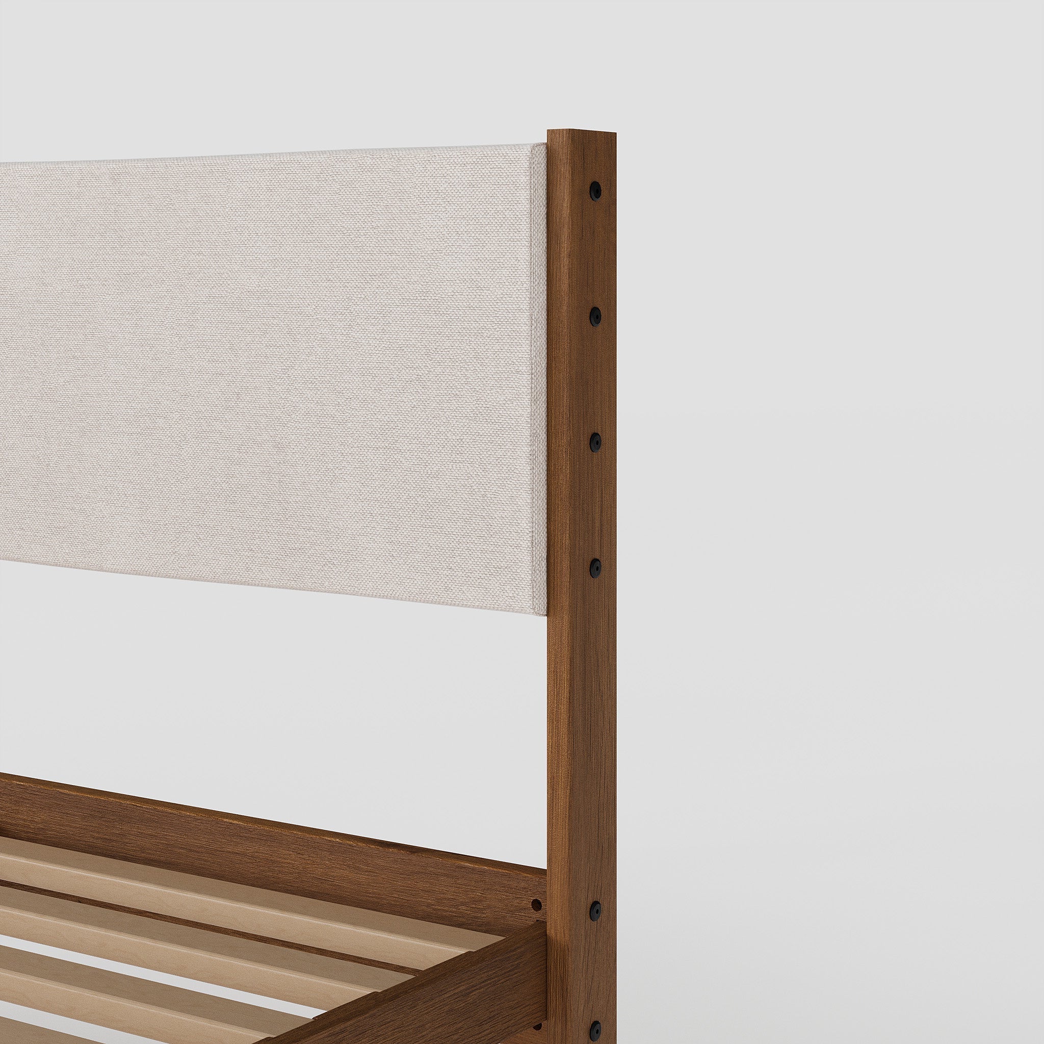 Wooden bed frame with a beige headboard on a white background